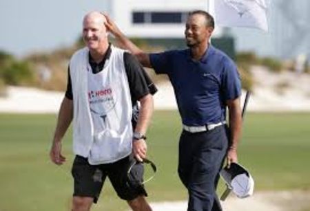 Tiger Woods in dark blue pats the head of Joe LaCava.